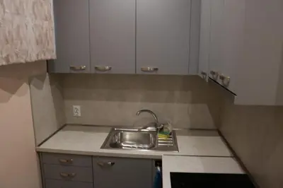 a small kitchen with a sink and white cabinets at Студио Морски бриз in Pomorie