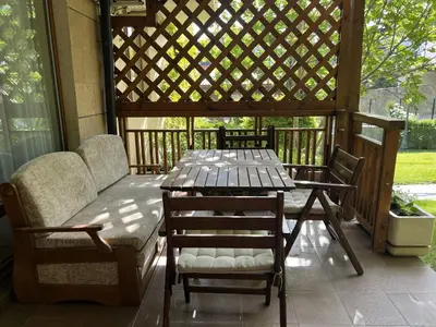 a table and chairs on a porch with a pergola at Аpartment in the Garden of Eden in Sveti Vlas
