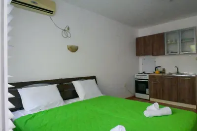 a bedroom with a green bed and a kitchen at NeV Getaway for 2 in Burgas City