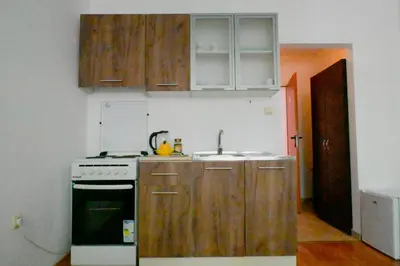 a kitchen with wooden cabinets and a sink and a stove at NeV Getaway for 2 in Burgas City