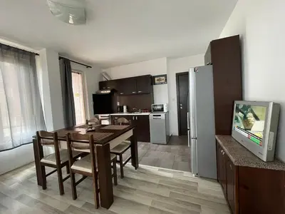 a living room with a dining room table and a kitchen at Adagio Sarafovo in Burgas City