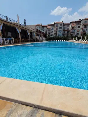 a large blue swimming pool with chairs and buildings at Famagusta Antoniya in Aheloy