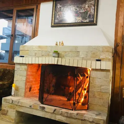 a stone fireplace with a fire in it at Вила НАДЕЖДА in Byala