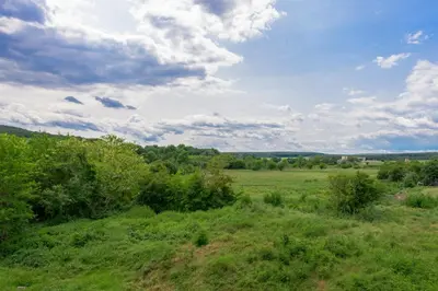 a green field with trees and clouds in the sky at Azur Properties ap50 in Shkorpilovtsi