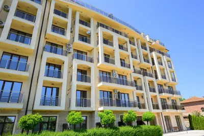 a yellow building with trees in front of it at Azur Properties ap50 in Shkorpilovtsi