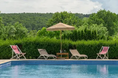 three chairs and an umbrella next to a swimming pool at Azur Properties ap51 in Shkorpilovtsi