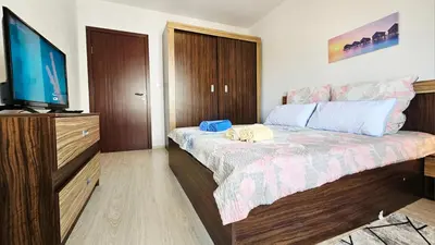 a bedroom with a bed and a flat screen tv at Апартамент Комфорт in Varna City
