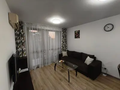 a living room with a couch and a clock on the wall at Kalia D11 Słoneczny Brzeg Sunny Beach in Sunny Beach