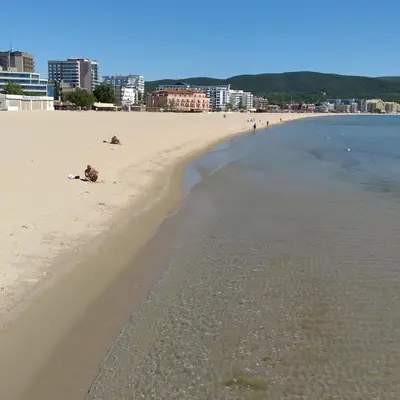a beach with people sitting on the sand and the water at Квартира студия Villa Astoria 2 Болгария Солнечный берег in Elenite