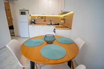 a kitchen with a wooden table and white cabinets at Next to Harmanite Beach - 1 BD Flat with Own Parking spot by Flat Mаnager in Sozopol