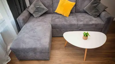 a grey couch with a white coffee table and a yellow pillow at Sea Holiday 21 in Burgas City
