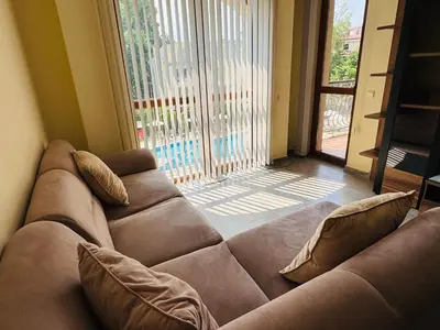 a brown couch in a living room with a large window at KALIA C9 One Bedroom Apartment in Sunny Beach