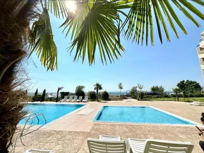 a swimming pool with chairs and a palm tree at Ipanema Beach - new - luxury first line - sea view in Sveti Vlas