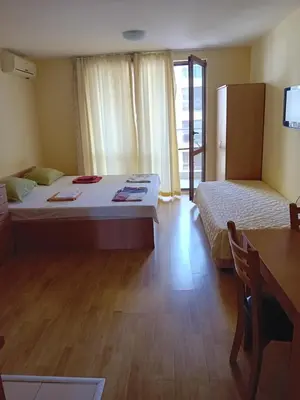 a bedroom with two beds and a table and a desk at Студио във Виго Панорама Несебър in Nesebar