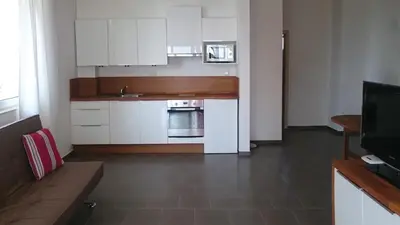 a small kitchen with white cabinets and a television at High in the Sky Apartments in Sozopol