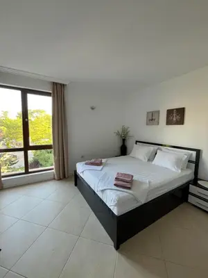 a bedroom with a bed and a large window at Двуспален апартамент Оазис Бийч Клуб in Lozenets