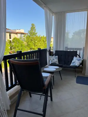 a balcony with two chairs and a table and a couch at Двуспален апартамент Оазис Бийч Клуб in Lozenets
