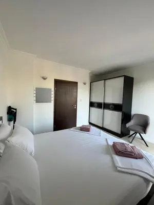 a bedroom with a large white bed and a chair at Двуспален апартамент Оазис Бийч Клуб in Lozenets