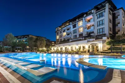 a large swimming pool with lounge chairs in front of a building at Двуспален апартамент Оазис Бийч Клуб in Lozenets