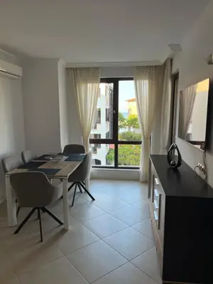 a dining room with a table and chairs and a window at Двуспален апартамент Оазис Бийч Клуб in Lozenets