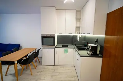 a kitchen with white cabinets and a wooden table at Harmani Haven 1BD Apartment with Own Parking spot by Flat Manаger in Sozopol