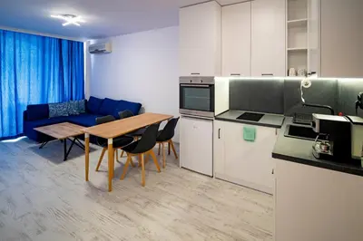 a kitchen and dining room with a table and a blue couch at Harmani Haven 1BD Apartment with Own Parking spot by Flat Manаger in Sozopol