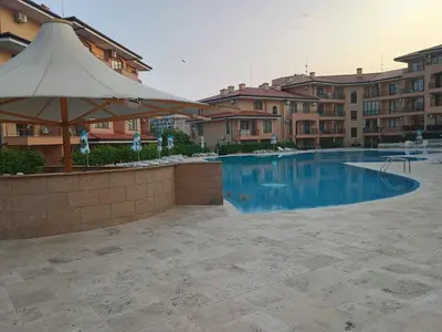 a swimming pool with an umbrella and some buildings at Sky dreams Sveti Vlas in Sveti Vlas