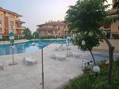 a pool with chairs and umbrellas next to a building at Sky dreams Sveti Vlas in Sveti Vlas