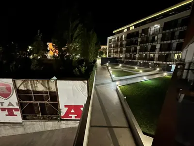 a night view of a building with a green lawn at PSB Apartment in Paradiso in Nesebar