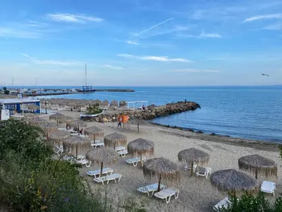 a beach with chairs and straw umbrellas and the ocean at Grand Villa luxury apartment with sea view in Sveti Vlas
