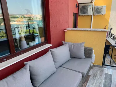 a couch sitting next to a window on a balcony at Seaview Young Family - Семейство на Черно море in Aheloy