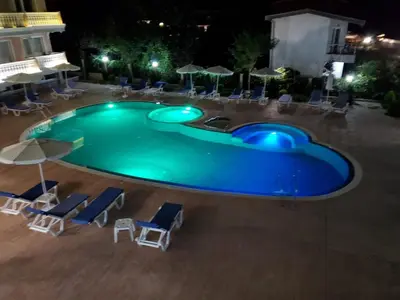 a swimming pool at night with chairs and umbrellas at Apartman RS in Lozenets