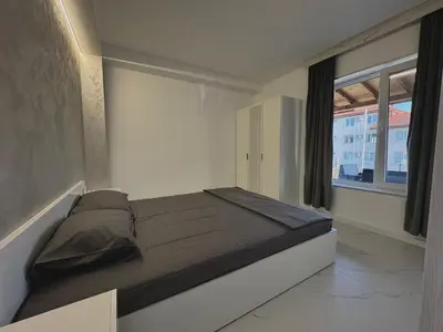 a bed in a room with a large window at Seagull Apartments in Byala
