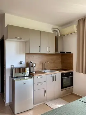 a kitchen with white cabinets and a sink at Sunset Deluxe in Kosharitsa