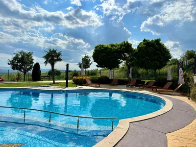a large swimming pool with chairs and trees at Sunset Deluxe in Kosharitsa