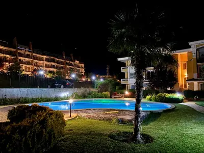 a palm tree next to a swimming pool at night at Sunset Deluxe in Kosharitsa