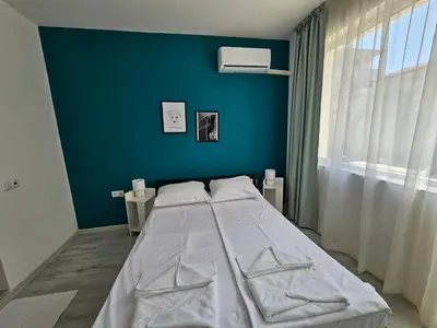 a bed in a room with a blue wall at Естрела къща за гости in Ravda