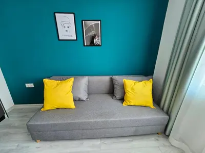 a couch with two yellow pillows and a blue wall at Естрела къща за гости in Ravda