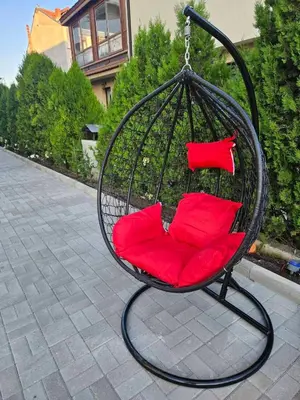 a swing chair with red pillows on a patio at Естрела къща за гости in Ravda