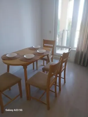 a wooden table and chairs in a room at Апартамент Бяла in Byala