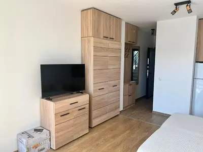 a bedroom with a large wooden cabinet with a tv at Modern Comfort Studio with Terrace Tsarevo in Tsarevo