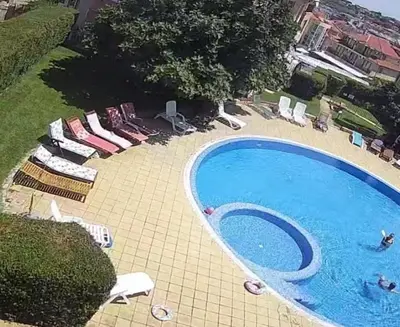 a swimming pool with chairs and people in it at Akrotiri 2BR Apartment in Sozopol