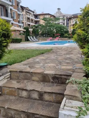 a stone walkway leading to a swimming pool with buildings at Studio Павлови Домус Екстра in Sveti Vlas
