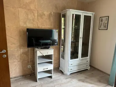 a living room with a tv and a cabinet at Shishkova Garden Apartments in Varna City
