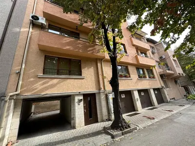 a building with a garage and a tree in front of it at Shishkova Garden Apartments in Varna City