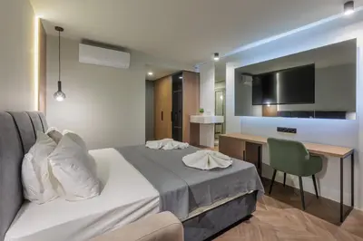 a bedroom with a bed and a desk with a television at Hotel Sea Sand in Sveti Vlas