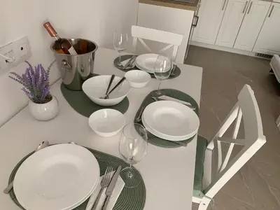 a white table with plates and wine glasses on it at BAMBOO BEACH STUDIO- Sozopol in Sozopol