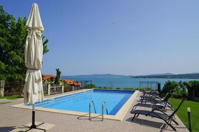 a pool with umbrellas and chairs next to the water at Six bedroom luxury villa with private pool in quiet residential area near beaches in Sozopol