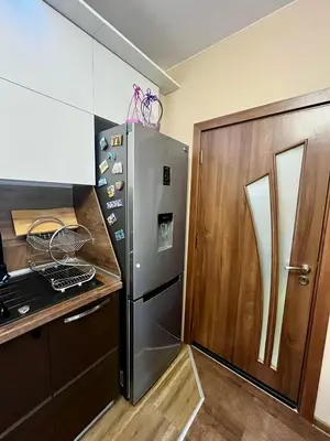 a kitchen with a stainless steel refrigerator next to a wooden door at Urban Nest Varna - Near Center and Bus Station in Varna City