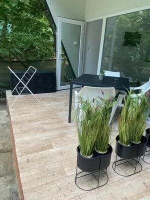 a patio with a black table and chairs and plants at Къмпинг Албатрос in Varna City
